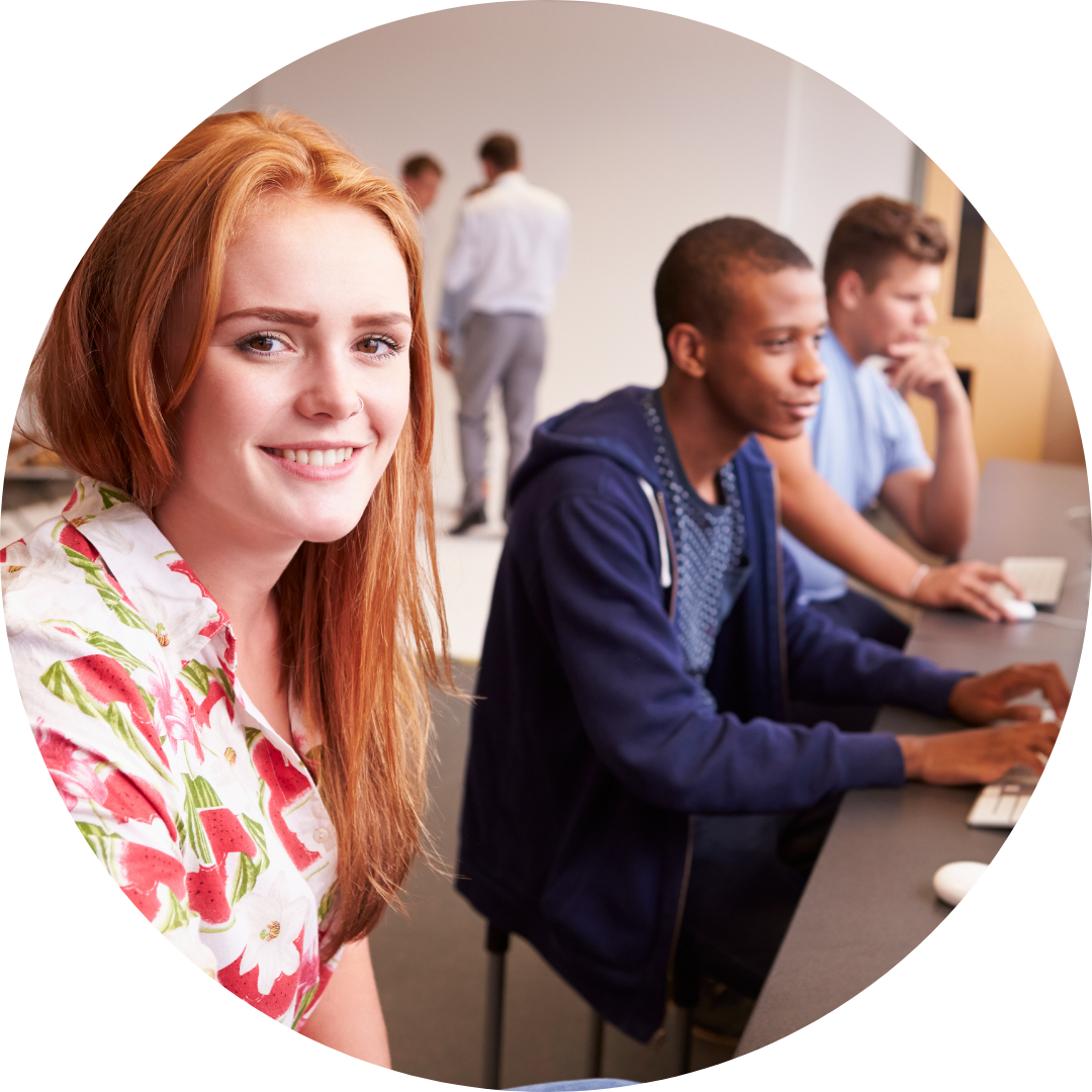  3 teens seated a computers